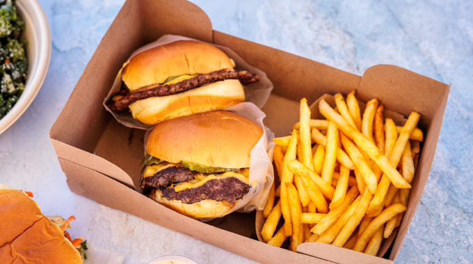 Two burgers and a serving of fries in a cardboard tray