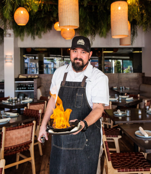 Chef Adam Titze holding a lit panela cheese