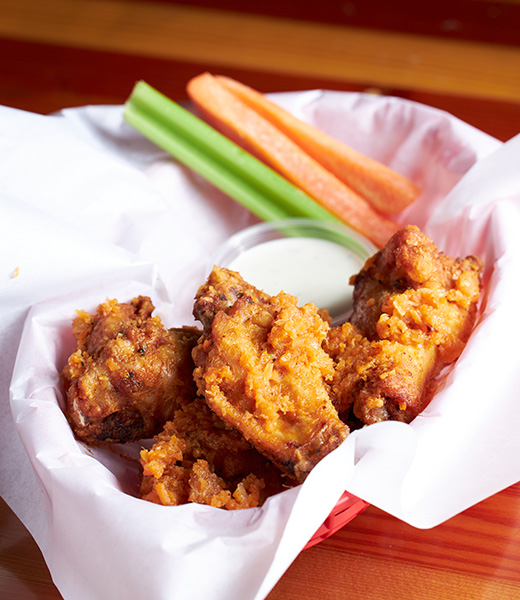 A basket of chicken wings with a side of celery and carrot sticks