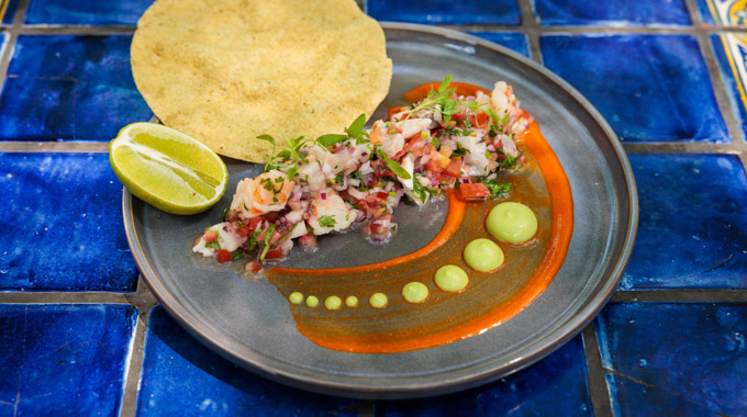 A plate of ceviche served beside a tostada and slice of lime
