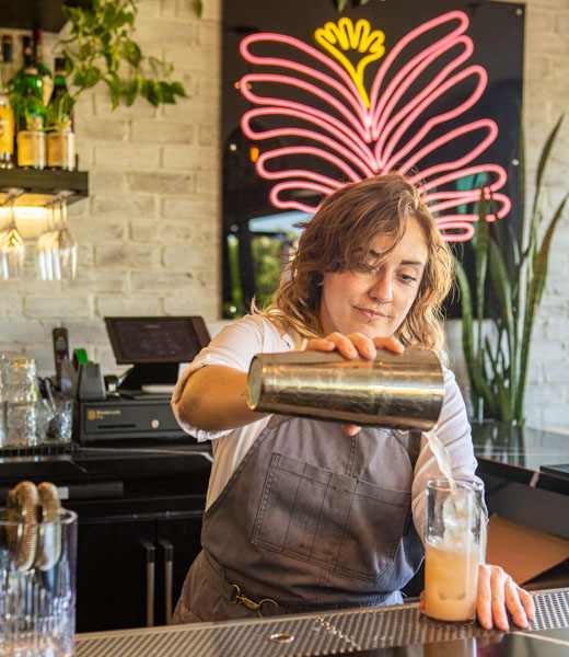 Barista pouring a drink into a tall glass