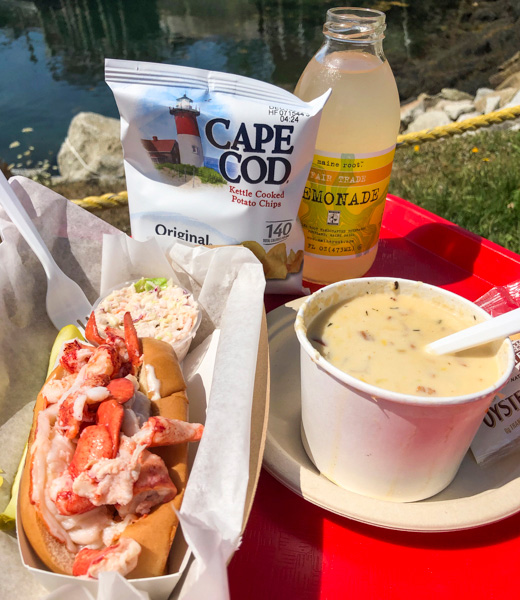 Lobster roll and corn chowder served with chips and lemonade.