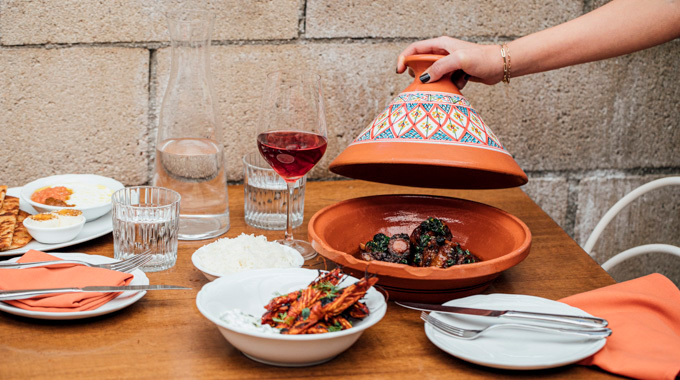 Someone lifting the lid of Bavel's Wagyu oxtail tagine