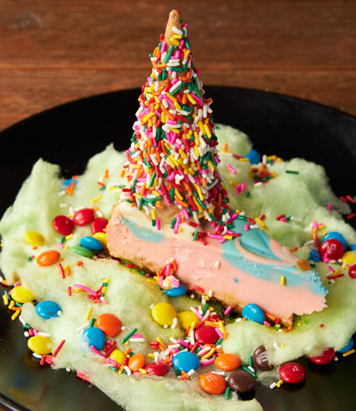 Colorful slice of cheesecake topped with a "horn" of sprinkles