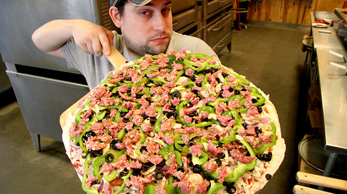 A pizza being loaded into the oven at Shakespeare’s Pizza