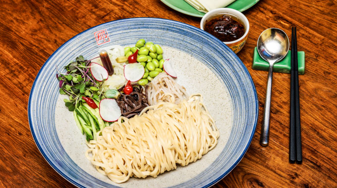 Noodles served in a bowl with toppings including mushroom and bean sprouts