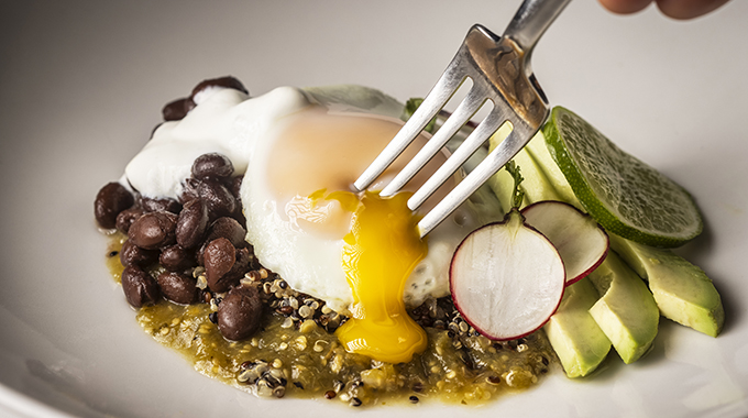 Egg yolk flowing over a serving of huevos rancheros