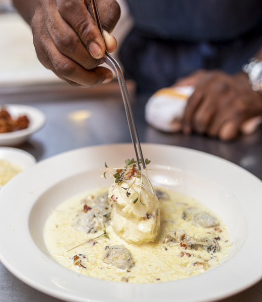 Chef Williams' oyster stew is served atop whipped potatoes, with a garnish of bacon bits, shredded Parmesan, and chopped chervil.