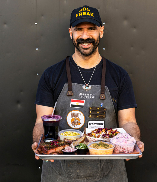 Kareem El Ghayesh carrying a tray filled with KGBBQ specialties.