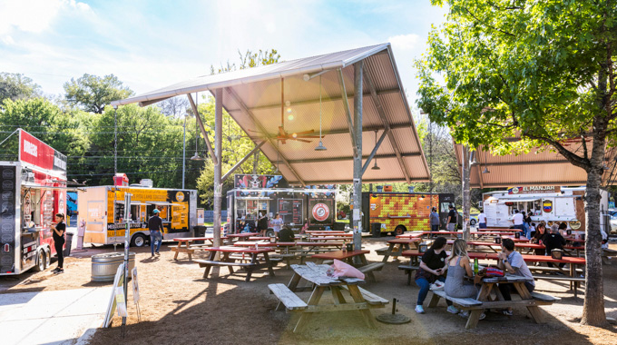 People eating on benches at The Picnic food truck park.