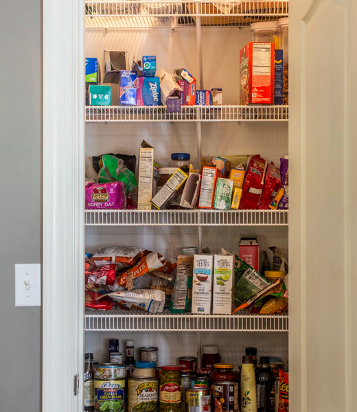A pantry crowded with open boxes, unsorted cans, and stacks of snack bags