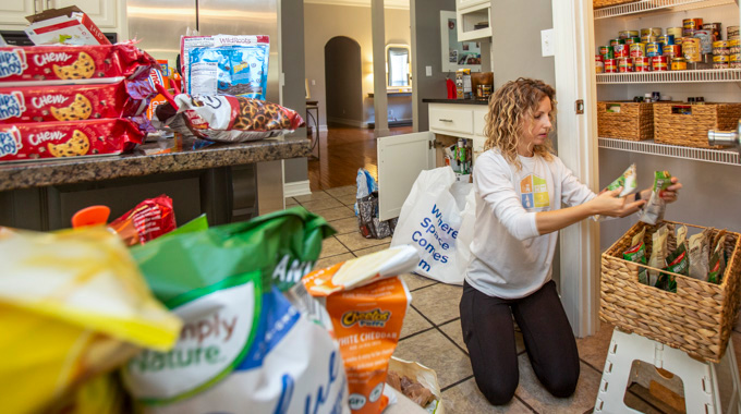 Kati Wadsworth sorting items into baskets in a client's kitchen