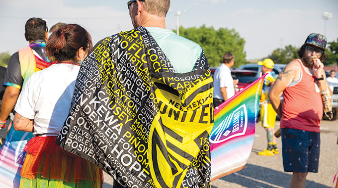 A fan wraps New Mexico United’s official flag around himself.