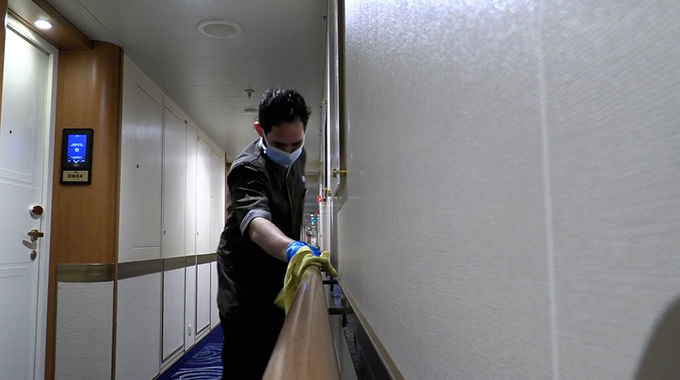 A Majestic Princess crew member wiping down a bannister