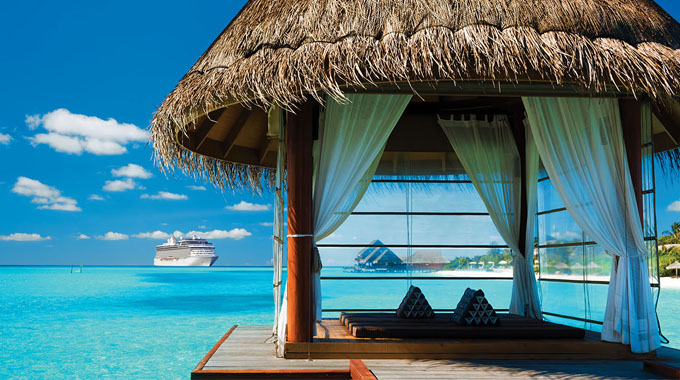 An overwater cabana, with a cruise ship seen in the distance
