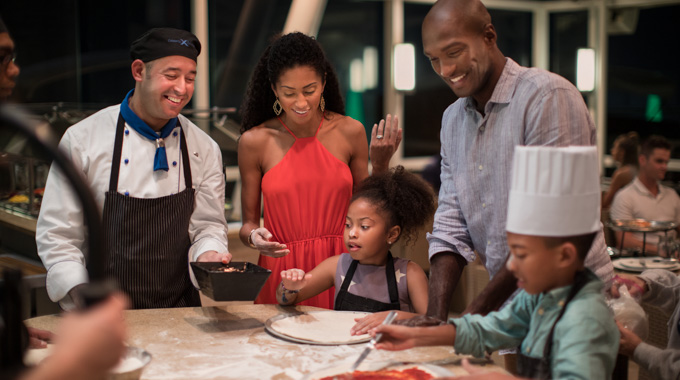 Parents watching as children make their own pizzas