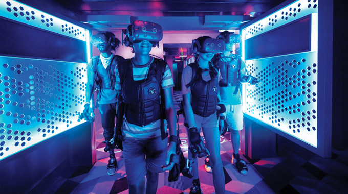 Teens wearing virtual reality headsets walking through the Virtual Reality Zone