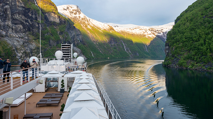 Cruisers watch the passing scenery from the deck of their ship