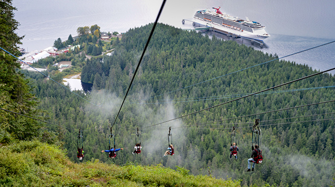 A cruise ship anchored in the distance as a group of people zipline