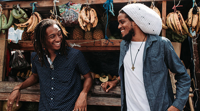 Two men in front of a fruit stand in Jamaica. | Photo by Getty Images