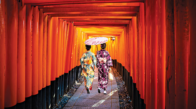 Women in traditional Japanese kimonos walk at Fushimi Inari Shrine in Kyoto, Japan. | Photo by Pawel/stock.adobe.com