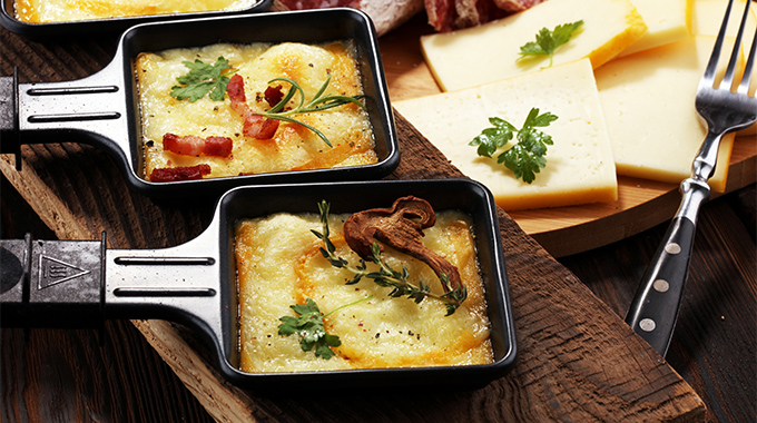 Traditional Swiss melted raclette cheese on diced boiled or baked potato. | Photo by beats/stock.adobe.com