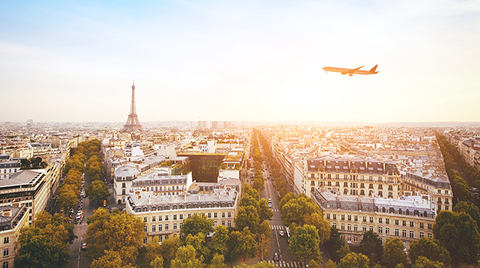 An airplane flies over Paris with Eiffel Tower in the background