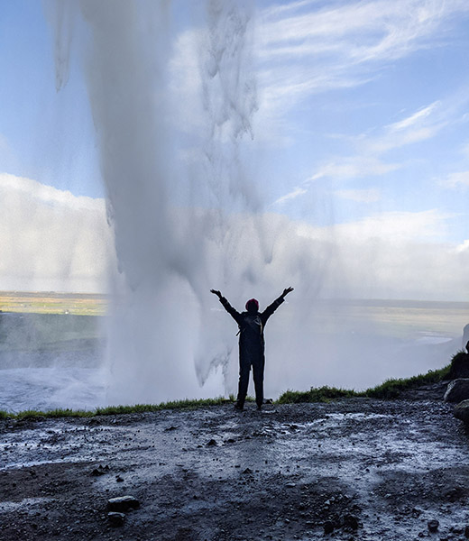 A visitor poses at Seljalandsfoss waterfall. | Photo by Jessica Fender