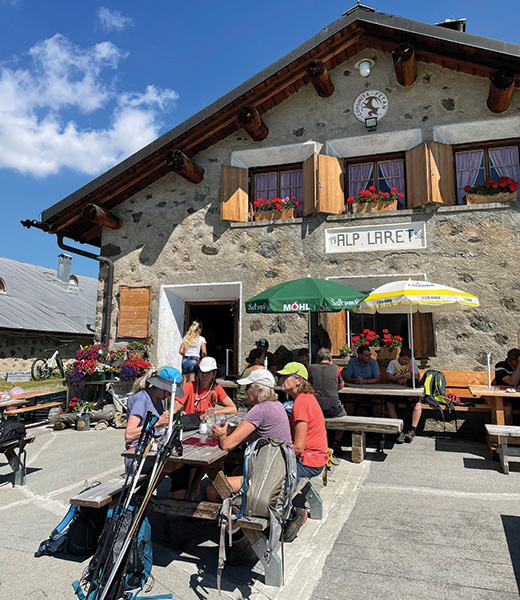 Hikers waiting for their lunch at a table outside the Alp Laret stone hut