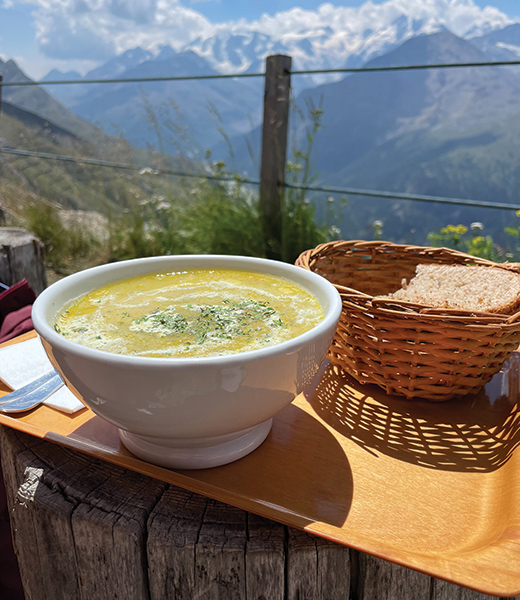 A bowl of soup served with a basket of bread