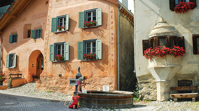 Two people filling buckets with water at the trough in Guarda