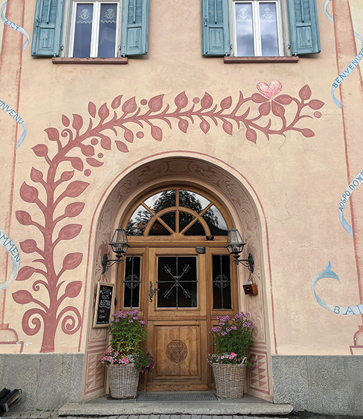 A painted vine wraps around an archway on the front of a house in Zuoz