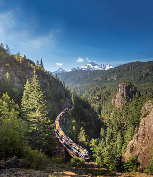 Rocky Mountaineer traveling through wooded mountains
