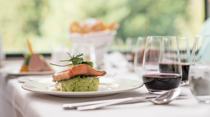 A salmon fillet served over rice and with a glass of red wine