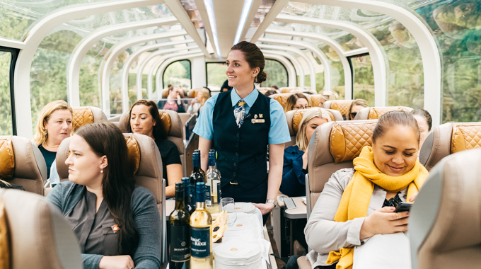 Rocky Mountaineer employee pushing a drink cart through the train car