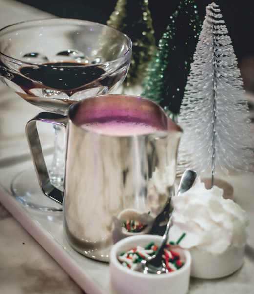 A tray of hot cocoa and toppings including whipped cream and sprinkles.