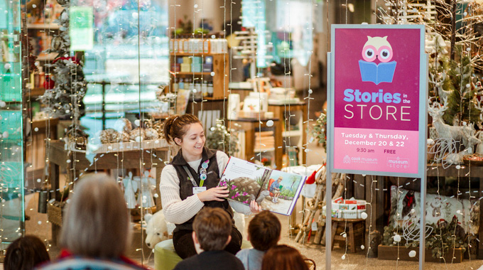 Cook Museum of Natural Science employee reading a book to a group of children.