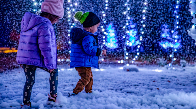 Two children walk through the snow at the Huntsville Botanical Garden
