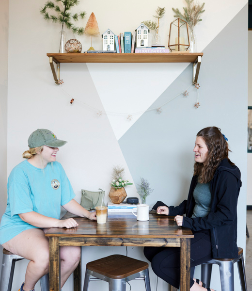 Two women chatting over coffee at a small table
