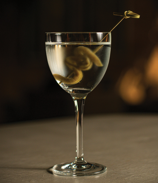 Glass of raicilla, a clear spirit, garnished with a sliver of pickeld cactus