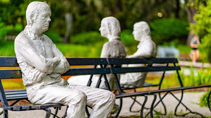 Statue of people sitting on metal benches