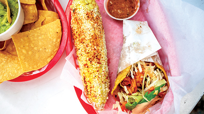 Taco served with street corn plus a side of chips and guacamole