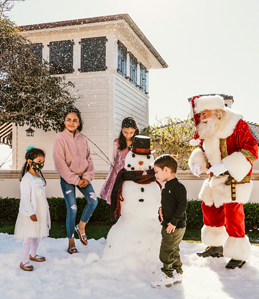 Santa greeting children beside a snowman.
