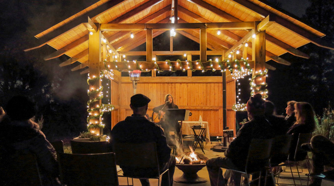 A performer sings while playing an acoustic guitar at the California Botanic Garden: Luminaria Nights