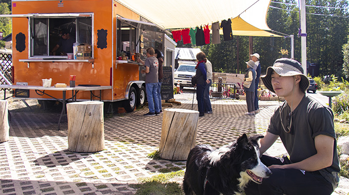 Young man and dog sitting in the shade near a food truck