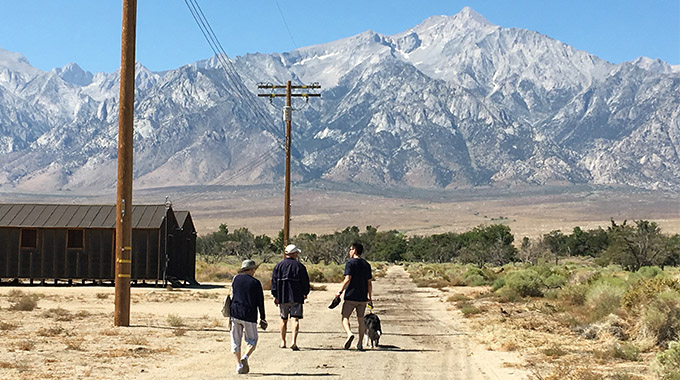 A trio of people and their dog walk the grounds of Manzanar National Historic Site