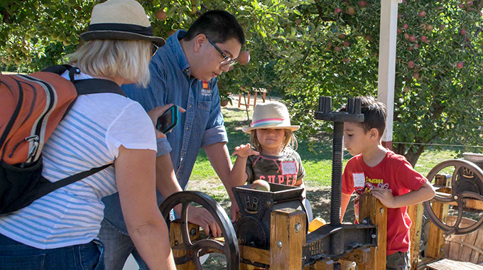 A family makes cider in a hand-cranked press at Willowbrook Farm in Oak Glen, California