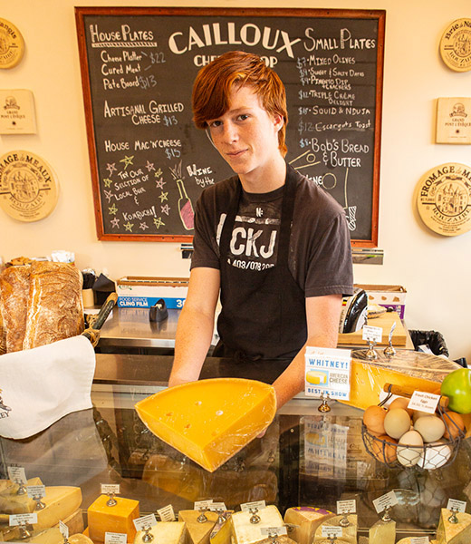 An employee behind the counter at Cailloux Cheese Shop