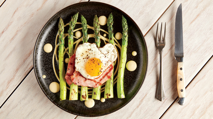 Slices of meat topped with an egg and served over a bed of asparagus