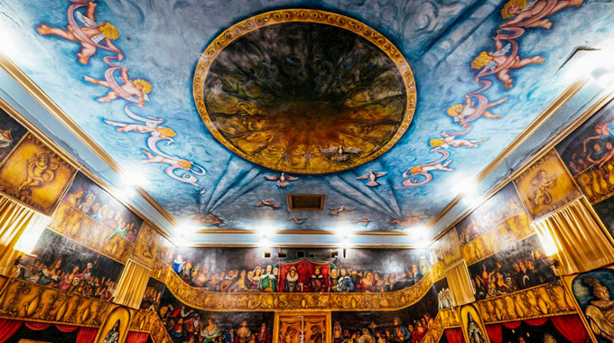 A detailed mural of an audience on the walls and cherubs on the ceiling inside the Amargosa Opera House